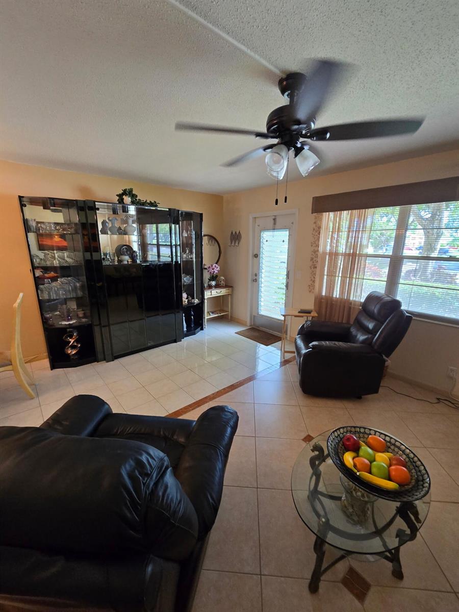 A living room features tile floors, a ceiling fan, a dark display cabinet, and furniture — 1030 Ashby D # 1030, Deerfield Beach FL 33442, DEERFIELD BEACH, FL
