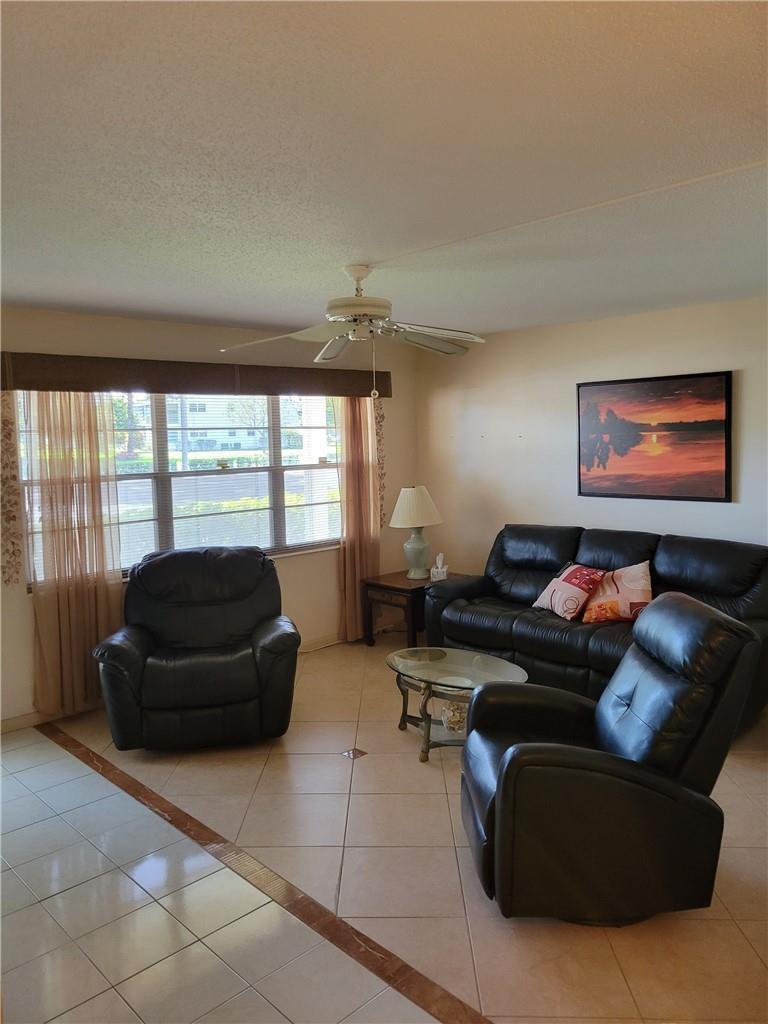 A living room with tile flooring, a ceiling fan, leather furniture, and a window — 1030 Ashby D # 1030, Deerfield Beach FL 33442, DEERFIELD BEACH, FL