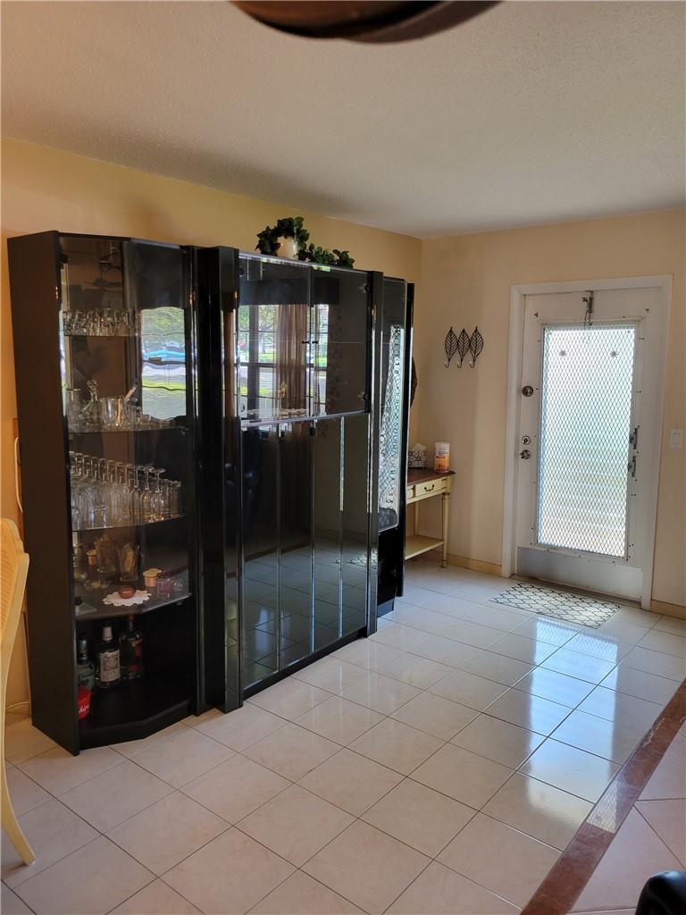 A tiled entryway features a large black display cabinet and a glass-paneled front door — 1030 Ashby D # 1030, Deerfield Beach FL 33442, DEERFIELD BEACH, FL