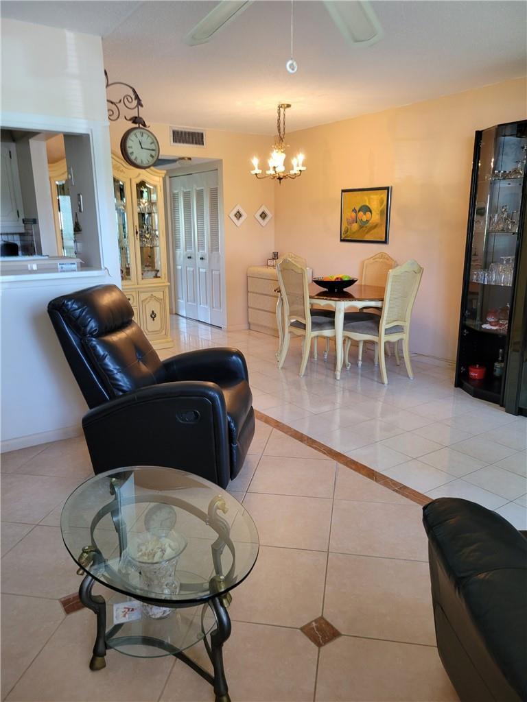 A living and dining area with tile floors, a black recliner, and a glass table — 1030 Ashby D # 1030, Deerfield Beach FL 33442, DEERFIELD BEACH, FL