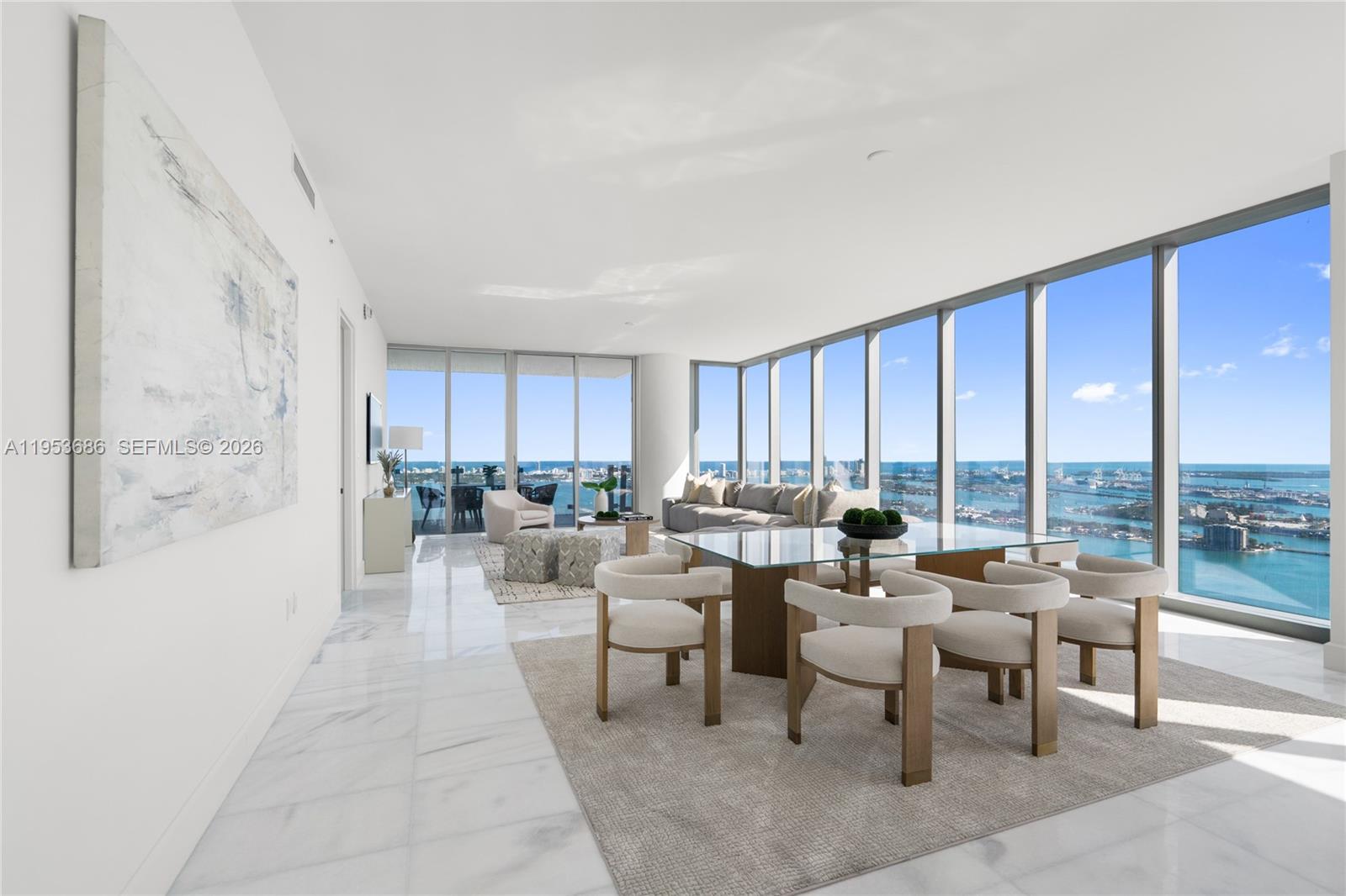 A modern dining and living area features floor-to-ceiling windows with expansive ocean and city views — 700 NE 26th Ter # 4903, Miami FL 33137, MIAMI, FL