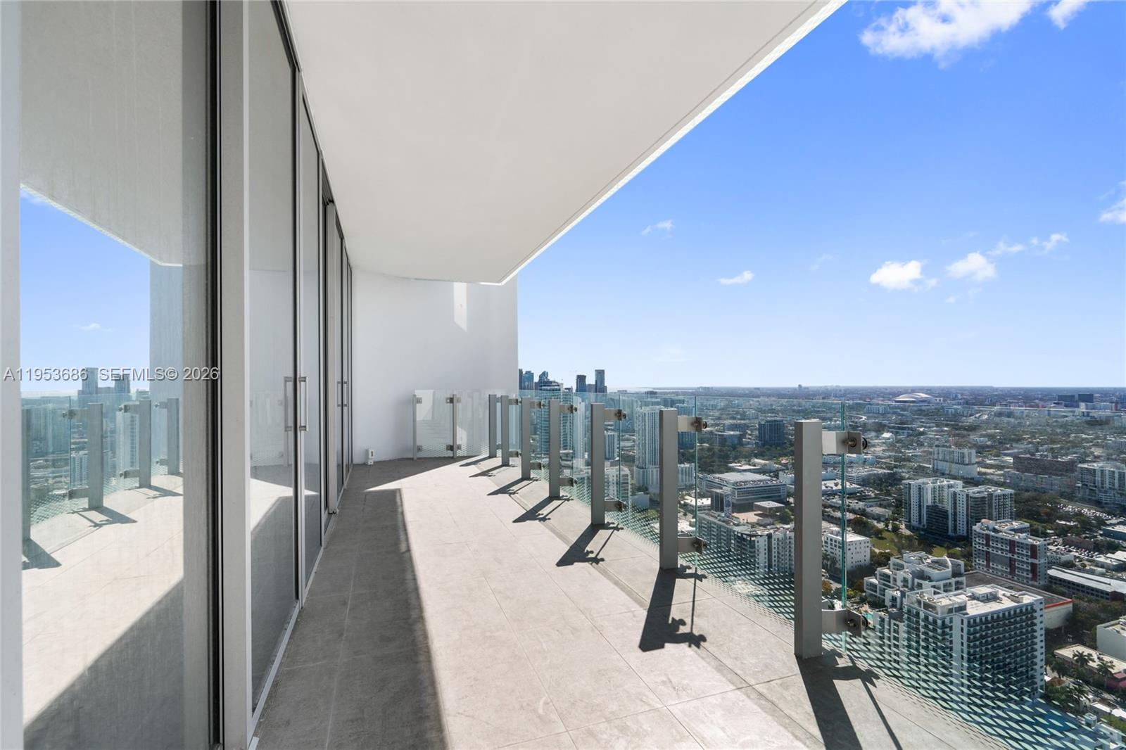 A high-rise balcony features glass railings and tile flooring overlooking a sprawling city skyline — 700 NE 26th Ter # 4903, Miami FL 33137, MIAMI, FL