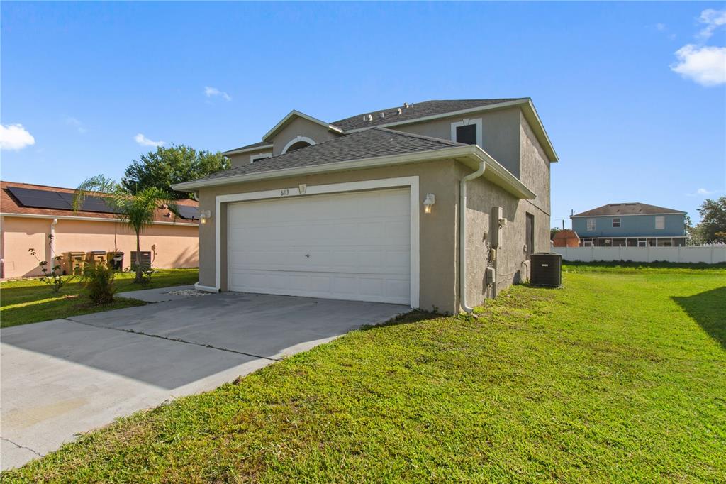 A two-story house with a beige stucco exterior and a white two-car garage — 613 NOTRE DAME WAY, KISSIMMEE, FL