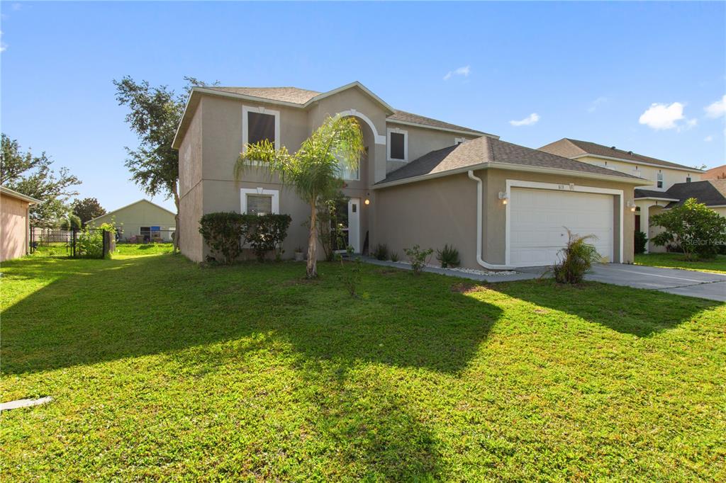 A two-story suburban house with a tan stucco exterior and an attached two-car garage — 613 NOTRE DAME WAY, KISSIMMEE, FL