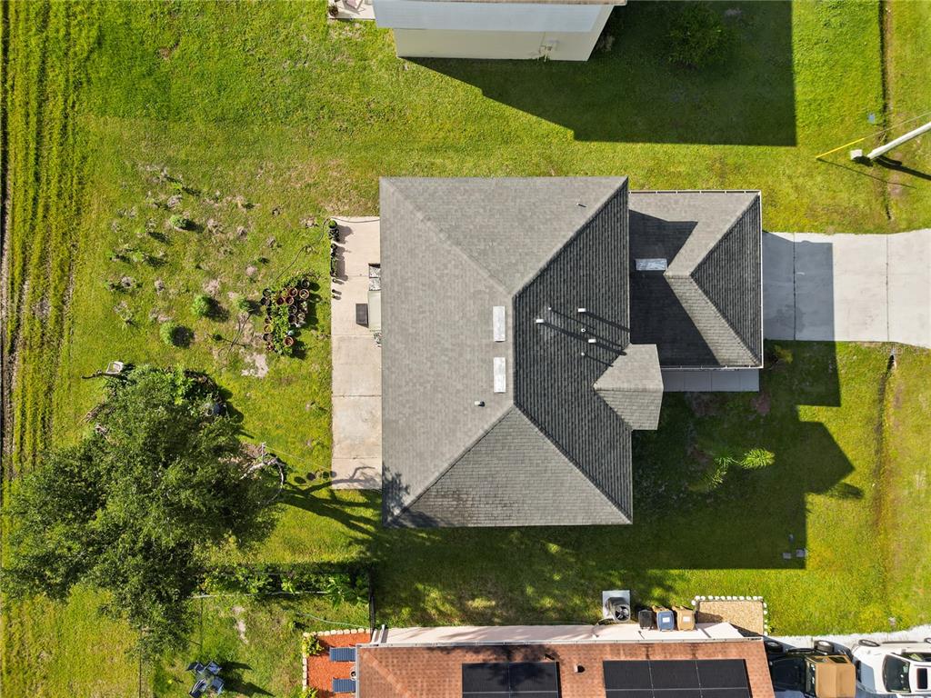 An aerial view shows a house with a dark shingled roof and a concrete patio — 613 NOTRE DAME WAY, KISSIMMEE, FL