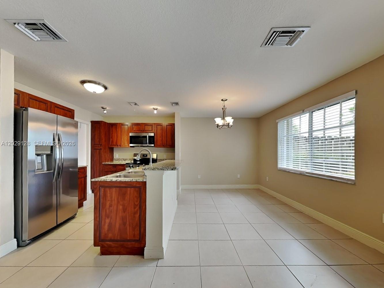 A kitchen with wood cabinets, stainless steel appliances, and a dining area with tile floors — BOYNTON BEACH, FL