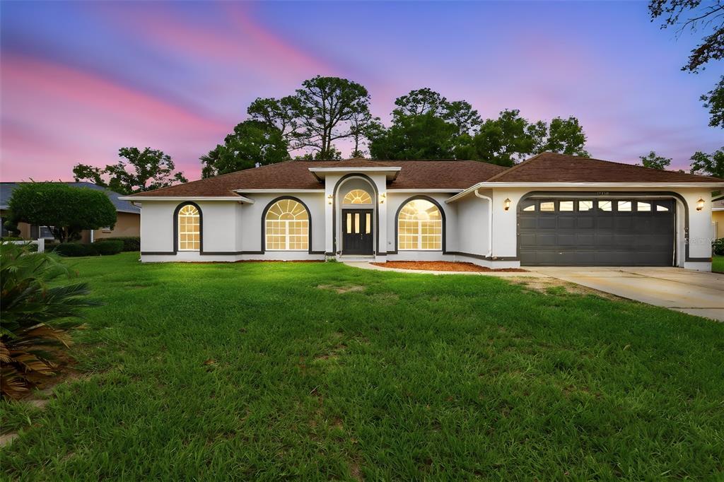 A single-story house with a white exterior, arched windows, and a dark garage door — 11355 SW 58TH CIRCLE, OCALA, FL