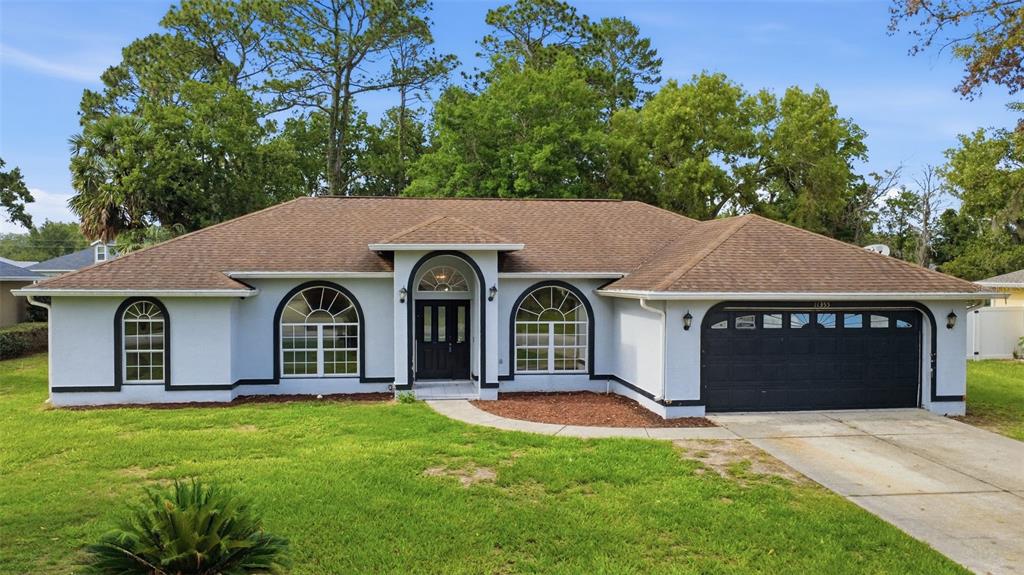 A single-story house with a light-colored stucco exterior, black trim, and a two-car garage — 11355 SW 58TH CIRCLE, OCALA, FL