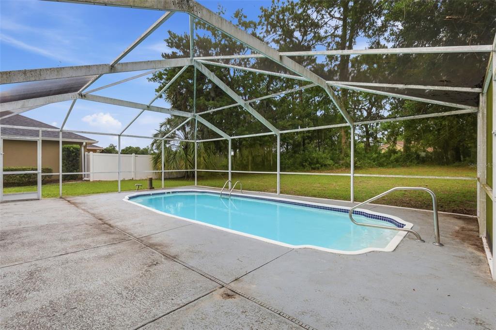 A rectangular swimming pool is enclosed by a screened lanai with a concrete deck — 11355 SW 58TH CIRCLE, OCALA, FL