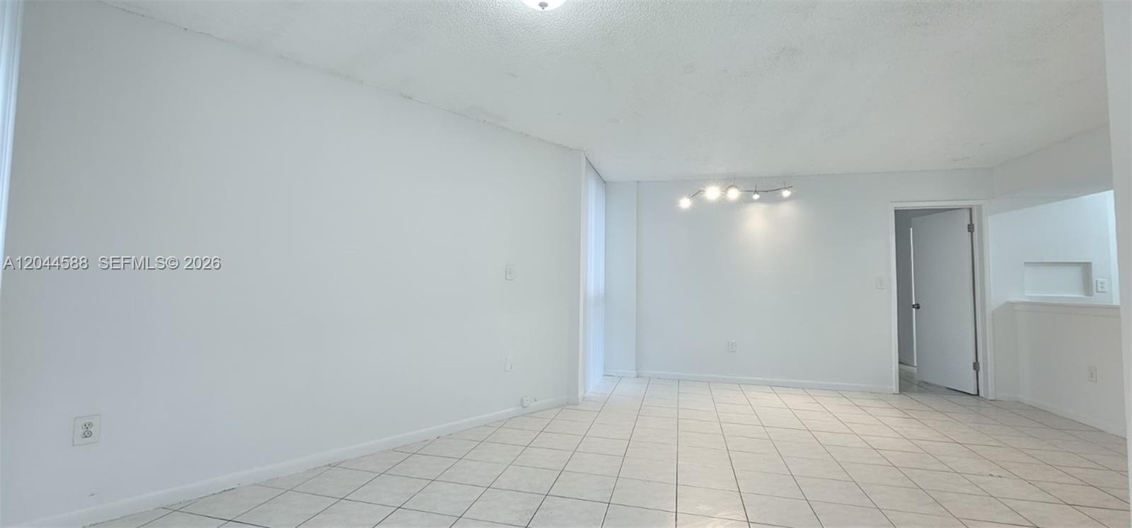 An empty room features white walls, tile flooring, and a modern ceiling light fixture — 7035 NW 186th St # D110, Hialeah FL 33015, HIALEAH, FL