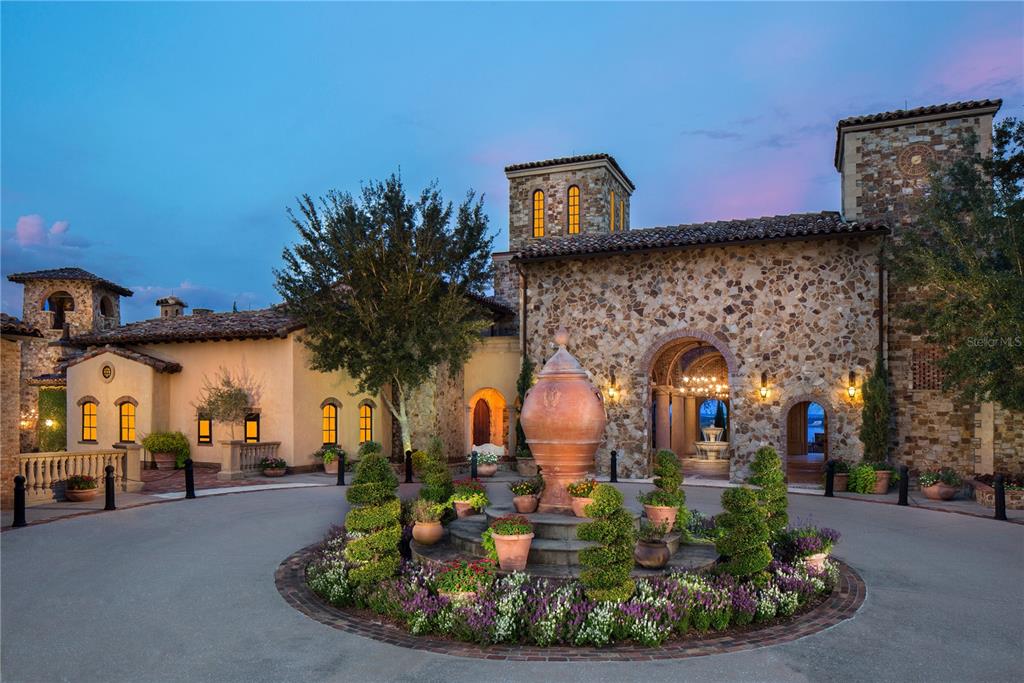 A circular driveway features a large stone fountain and landscaping in front of a stone villa — 15381 APENNINE WAY, MONTVERDE, FL