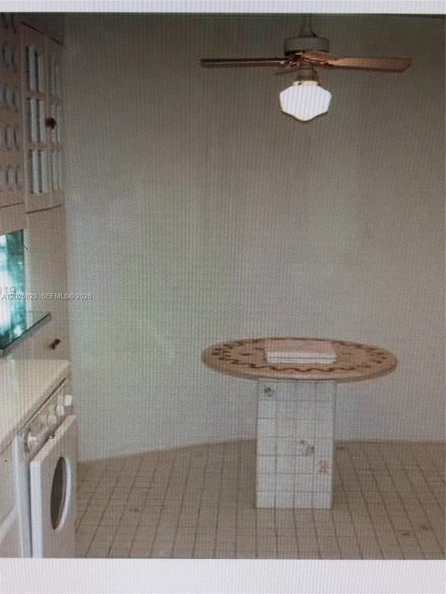 A kitchen features a tiled pedestal table, a ceiling fan, and white cabinetry — 1111 Crandon Blvd # B506, Key Biscayne FL 33149, KEY BISCAYNE, FL