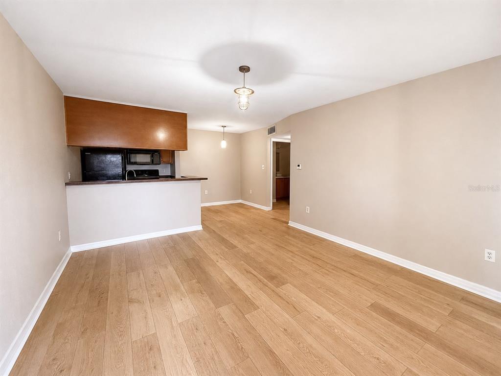 An open-concept living area features light wood-look flooring and a kitchen with a breakfast bar — 203 LAKE PARSONS GREEN UNIT 108, BRANDON, FL