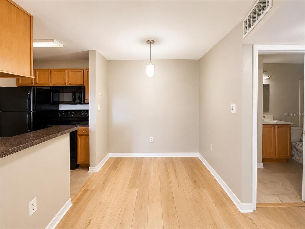 A dining area with light wood flooring, a pendant light, and an adjacent kitchen — 203 LAKE PARSONS GREEN UNIT 108, BRANDON, FL