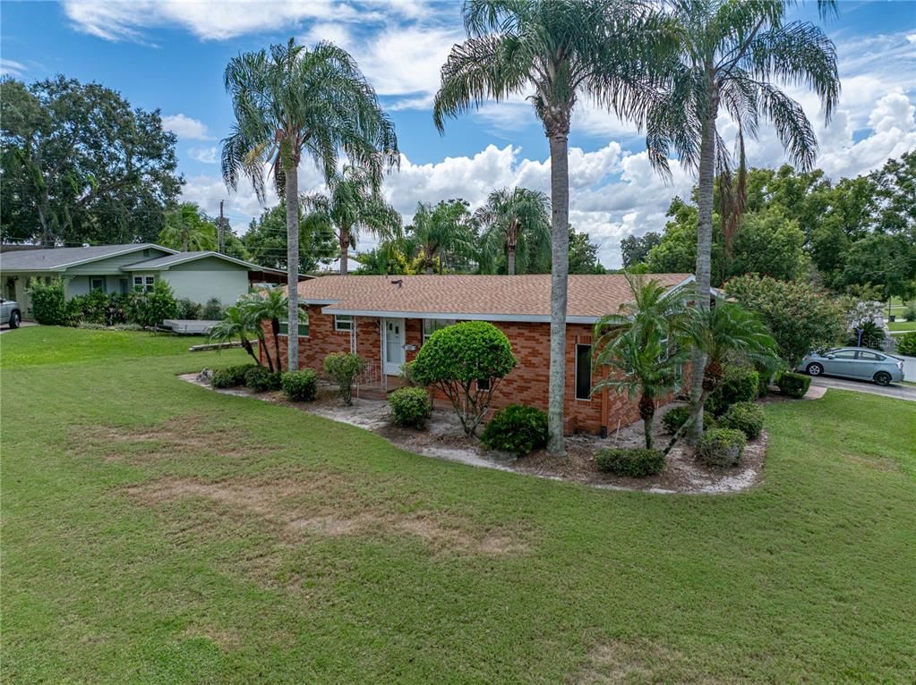 An exterior view of a single-story brick house with palm trees and a grassy lawn — 307 GLENDALE ST, LAKELAND, FL