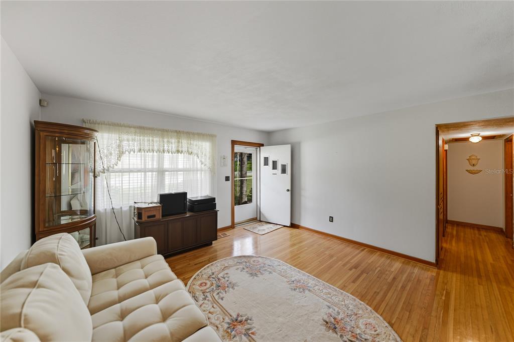 A living room features hardwood floors, a white sofa, a curio cabinet, and an entryway — 307 GLENDALE ST, LAKELAND, FL