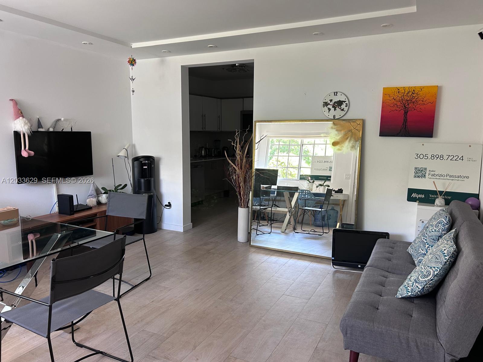 A living room features a grey sofa, a glass dining table, and a large floor mirror — 700 16th St # 109, Miami Beach FL 33139, MIAMI BEACH, FL