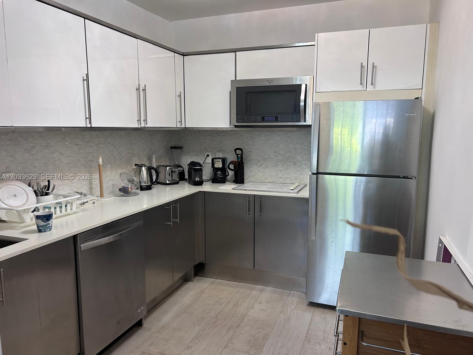 A kitchen features white upper cabinets, stainless steel lower cabinets, and stainless steel appliances — 700 16th St # 109, Miami Beach FL 33139, MIAMI BEACH, FL