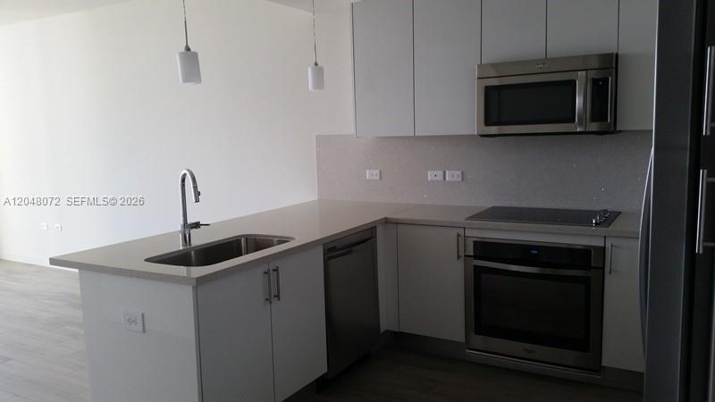 A modern kitchen features white cabinetry, stainless steel appliances, and a peninsula with a sink — 999 SW 1st Ave # 2510, Miami FL 33130, MIAMI, FL