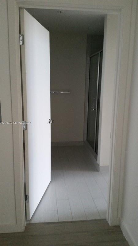 A white door opens into a bathroom with light-colored tile flooring and a glass shower — 999 SW 1st Ave # 2510, Miami FL 33130, MIAMI, FL
