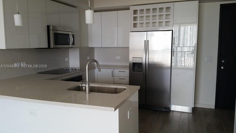 A modern kitchen features white glossy cabinets, stainless steel appliances, and a quartz countertop island — 999 SW 1st Ave # 2510, Miami FL 33130, MIAMI, FL