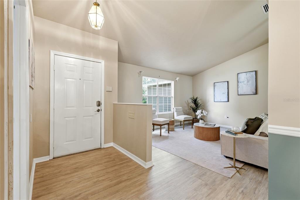 An entryway with wood-look flooring leads into a living room featuring a half-wall partition — 8158 SW 51ST BOULEVARD, GAINESVILLE, FL