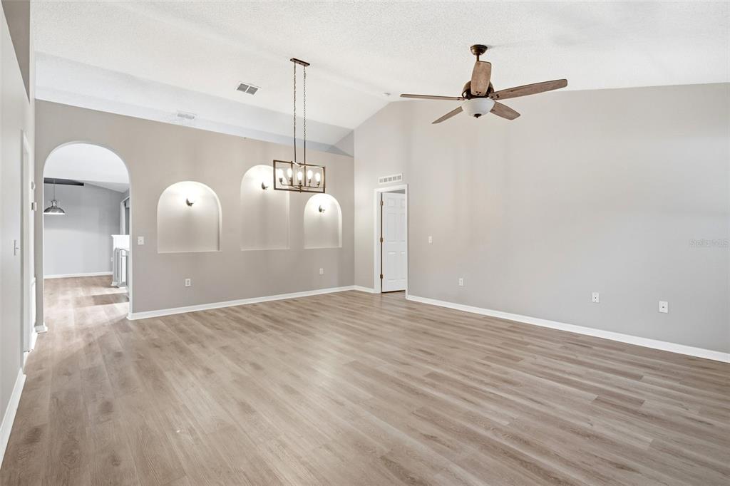 A dining room with vaulted ceilings, wood-look flooring, and three arched wall niches — 134 CROWN COLONY WAY, SANFORD, FL