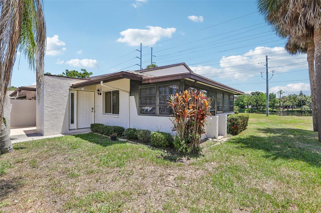 A single-story house with a white stucco exterior, a screened-in porch, and a grassy yard — 1418 14TH CIRCLE SE, LARGO, FL
