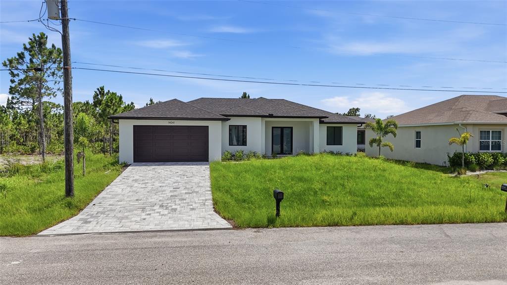 A single-story house with a white exterior, dark roof, and a paved driveway — 14041 NEWSON LANE, PORT CHARLOTTE, FL