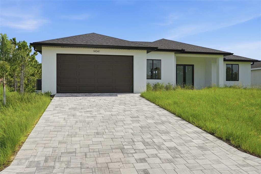 A white single-story house with a dark roof, a paved driveway, and a two-car garage — 14041 NEWSON LANE, PORT CHARLOTTE, FL