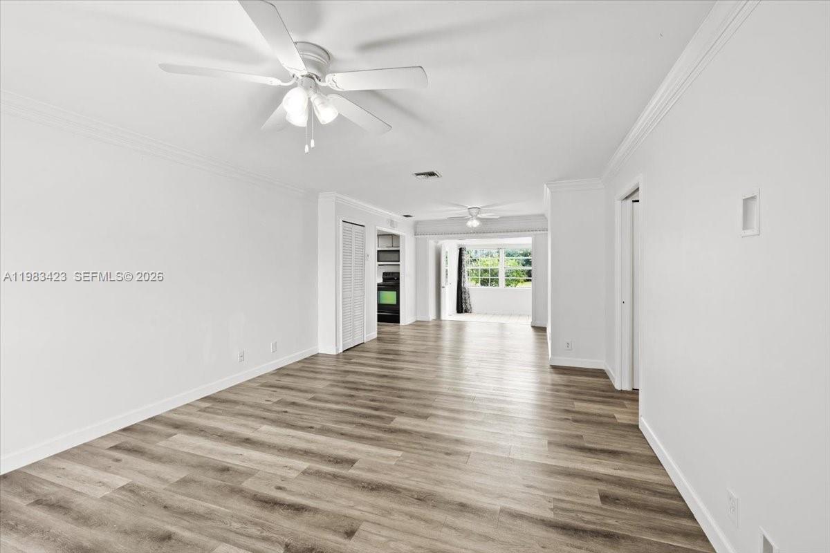 A bright, empty living room features wood-look flooring, white walls, and a ceiling fan — 7371 SW 1st St, Margate FL 33068, MARGATE, FL