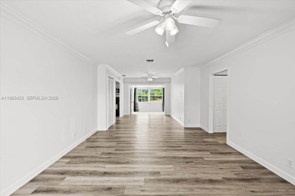 An empty room with wood-look flooring, white walls, and a ceiling fan leads to a patio — 7371 SW 1st St, Margate FL 33068, MARGATE, FL