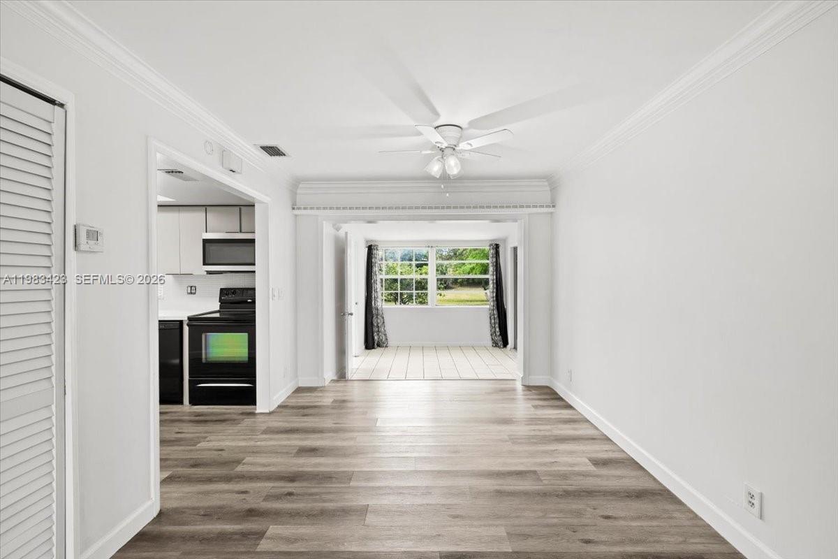 A living area with wood-look flooring leads to a kitchen and a sunroom beyond — 7371 SW 1st St, Margate FL 33068, MARGATE, FL