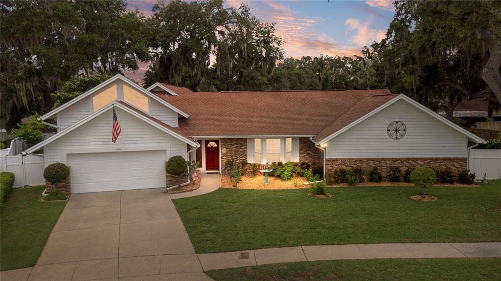 A single-story house with a white garage, brick accents, and a red front door — 1516 TEAKWOOD DRIVE, PLANT CITY, FL
