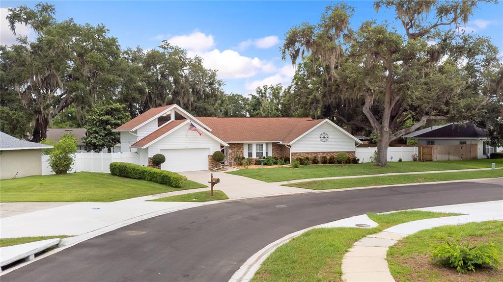 A single-story house with a white garage, brown roof, and large trees in the yard — 1516 TEAKWOOD DRIVE, PLANT CITY, FL