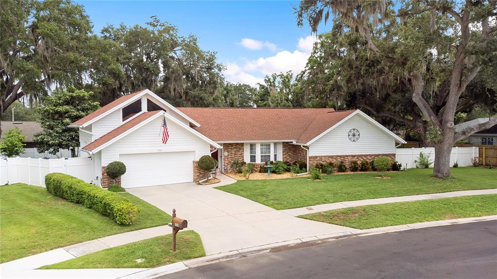 A single-story house with a white garage, brick accents, and a large front lawn — 1516 TEAKWOOD DRIVE, PLANT CITY, FL