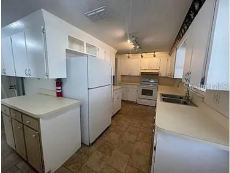 A kitchen with white cabinets, a white refrigerator, a stainless steel stove, and tiled floors — 1305 CARR DRIVE, AUBURNDALE, FL
