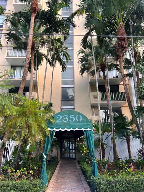 The exterior of a multi-story apartment building features a green awning over the entrance — 2350 NE 135TH STREET UNIT 209, NORTH MIAMI, FL