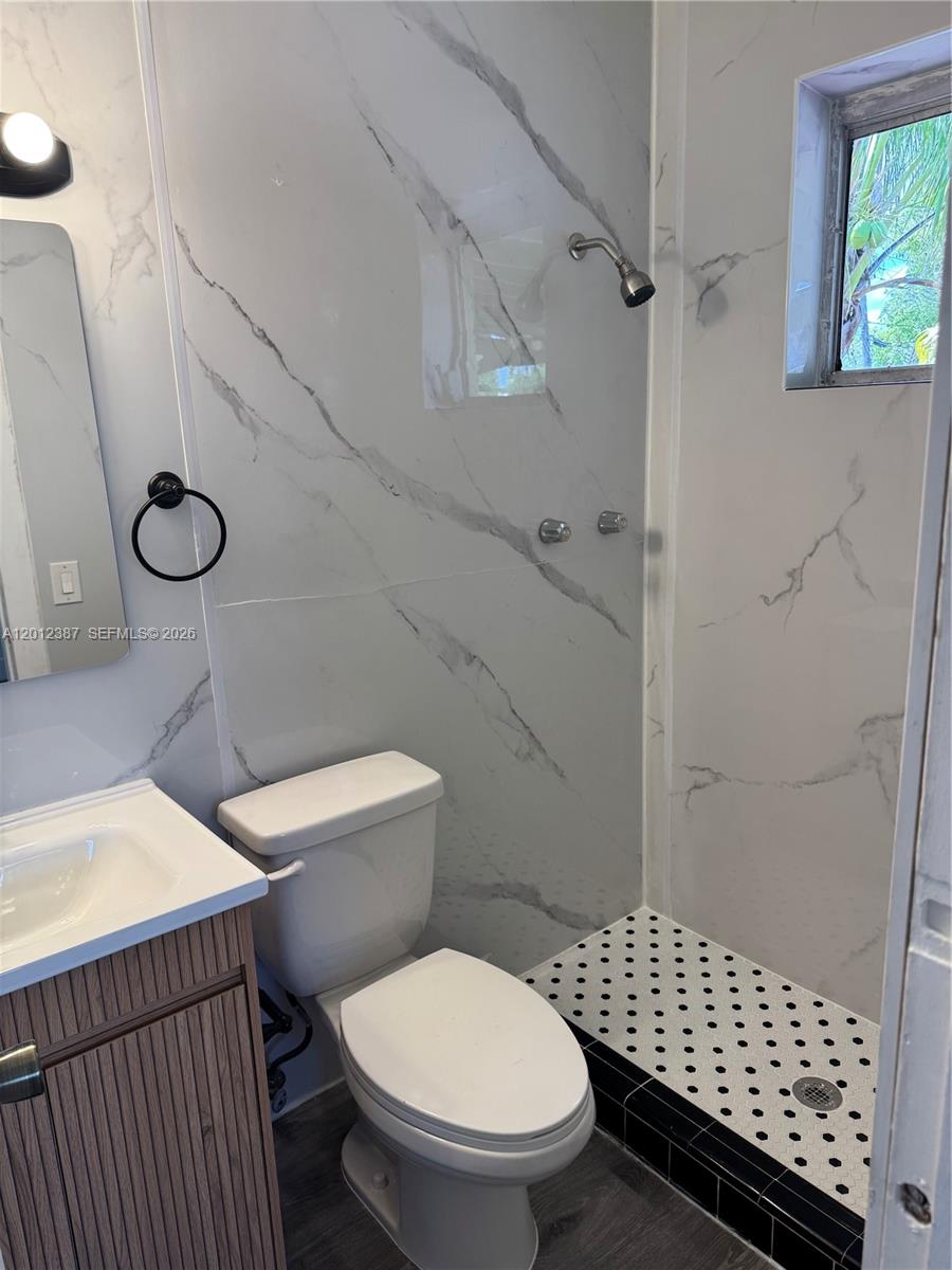 A kitchen with dark cabinets and granite countertops opens into a room with wood flooring — 2620 SW 53rd Ave, West Park FL 33023, WEST PARK, FL