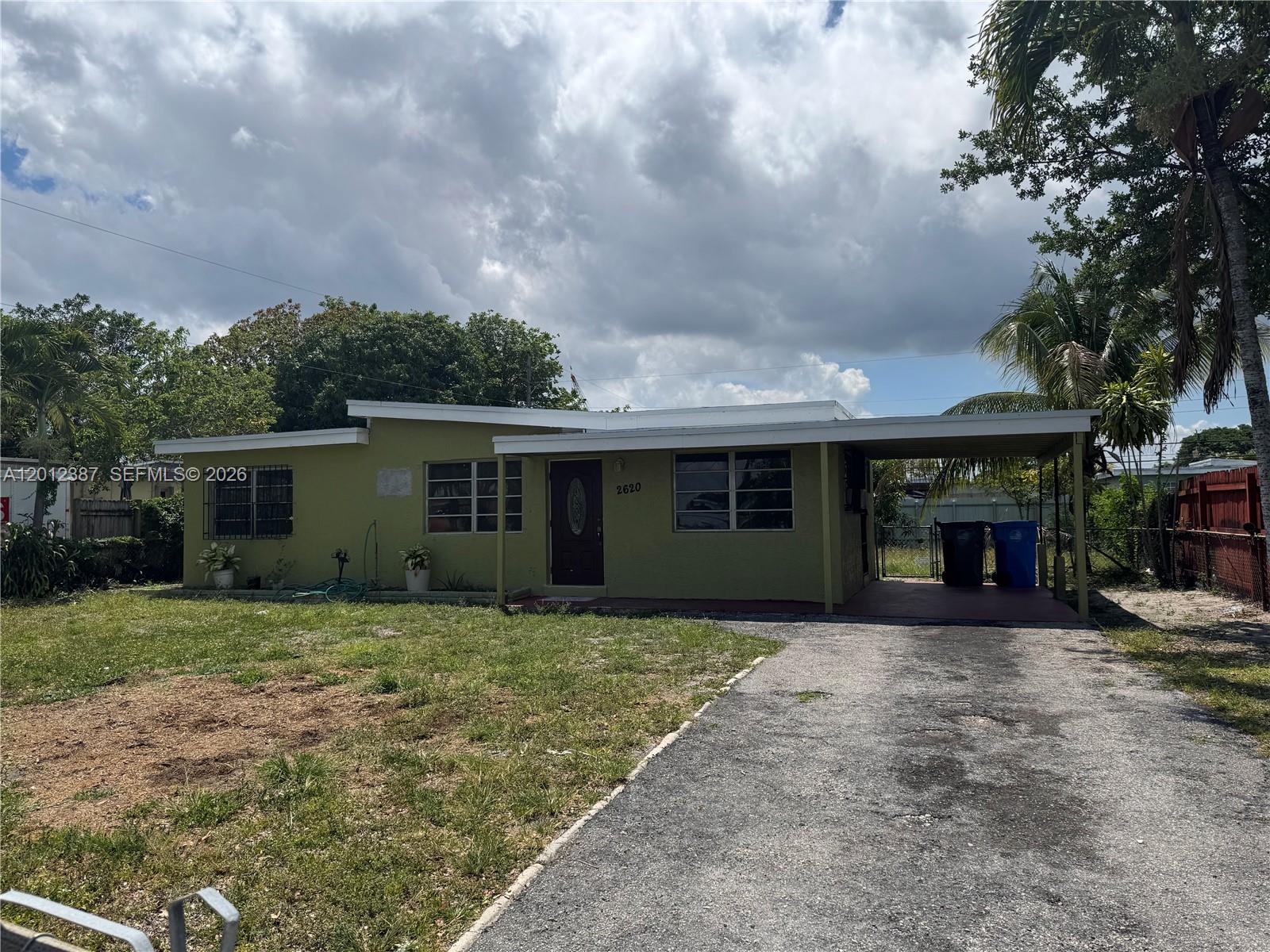 An empty room features gray wood-look flooring, white walls, and windows with security bars — 2620 SW 53rd Ave, West Park FL 33023, WEST PARK, FL