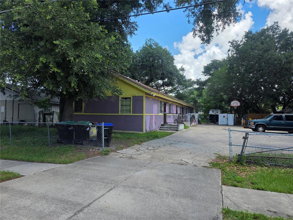 A purple and yellow single-story building with a concrete driveway and a chain-link fence — 4429 CYPRESS STREET, ORLANDO, FL
