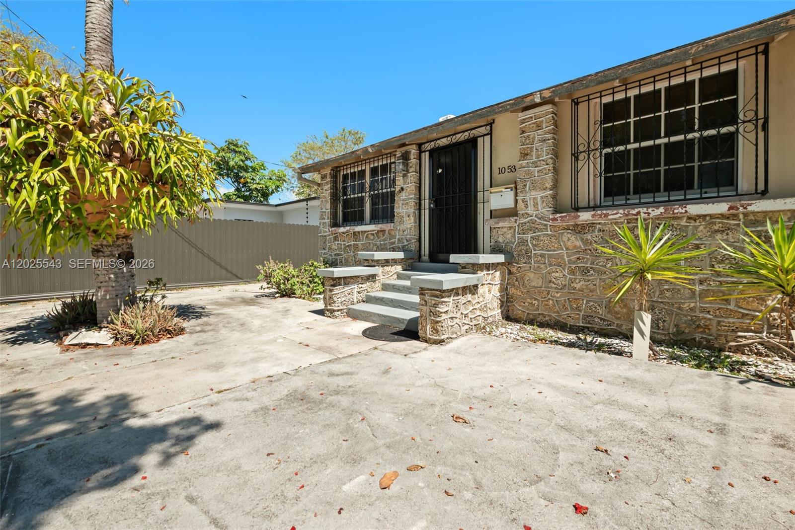 A stone-faced house exterior features a front entrance with steps and metal security bars — 1053 NW 28th St, Miami FL 33127, MIAMI, FL