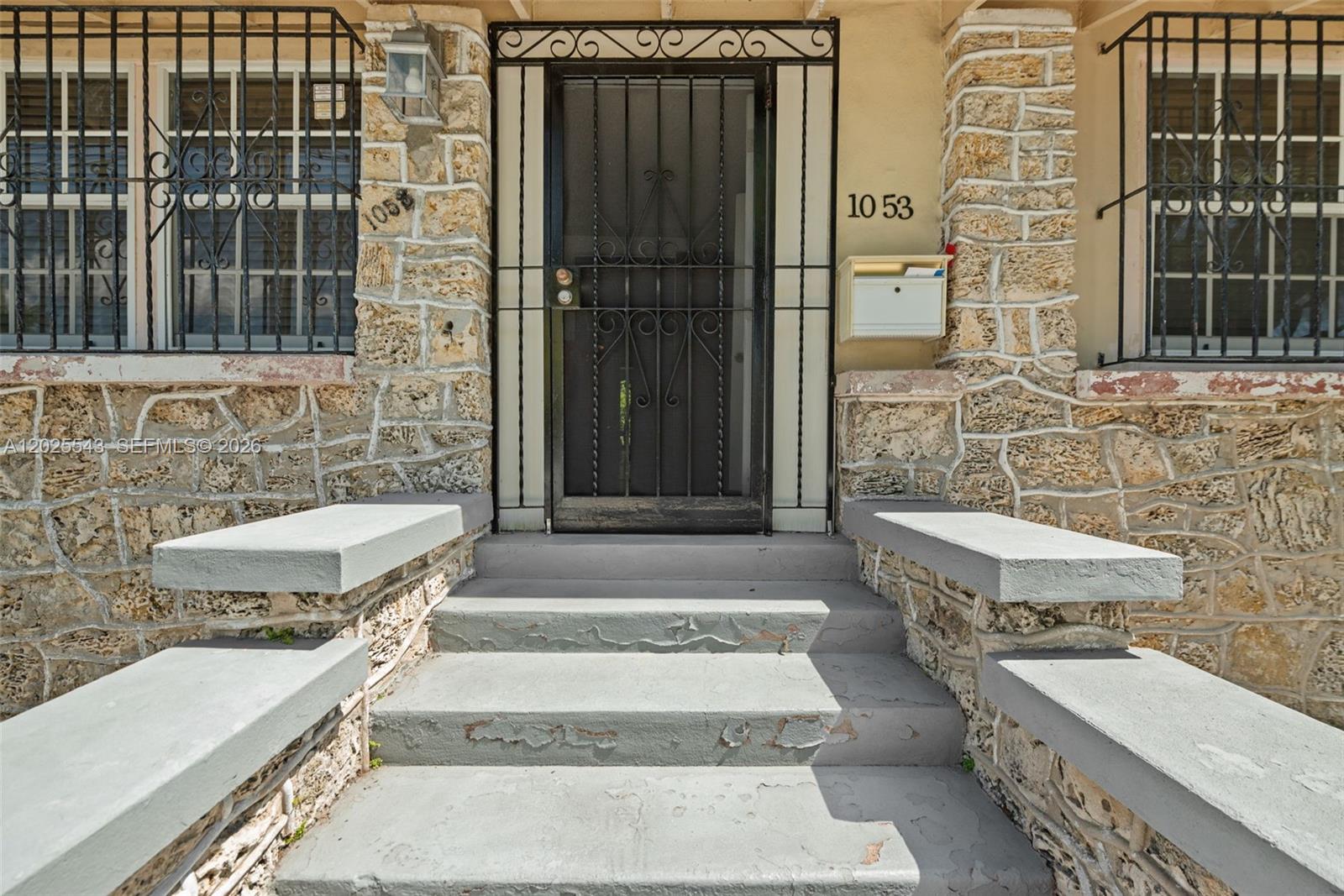 The exterior entrance features stone walls, a metal security door, and gray concrete steps — 1053 NW 28th St, Miami FL 33127, MIAMI, FL