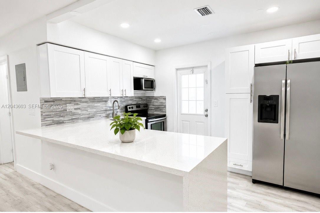 A modern kitchen features white cabinetry, stainless steel appliances, and a white quartz island — 59 E 10th St, Hialeah FL 33010, HIALEAH, FL