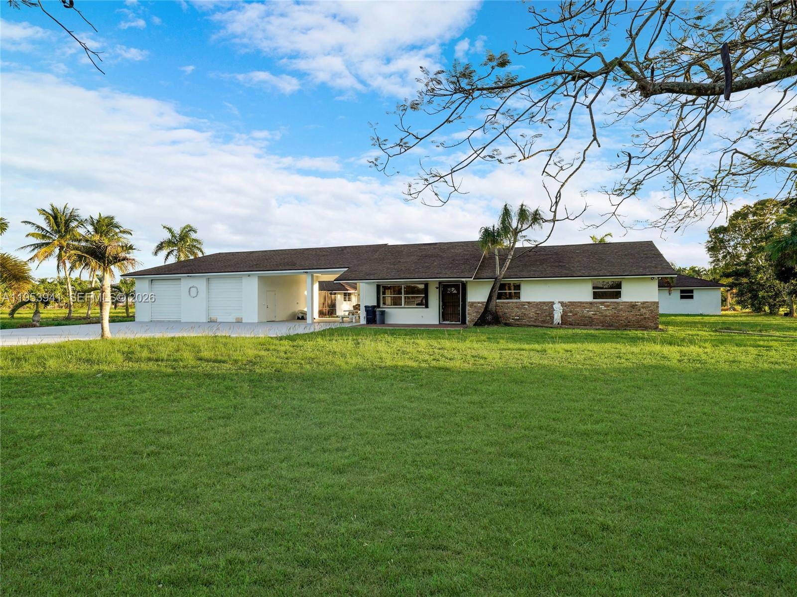 A single-story house with a white exterior, brick accents, and an attached garage sits on grass — 20000 SW 216th St, Miami FL 33170, MIAMI, FL