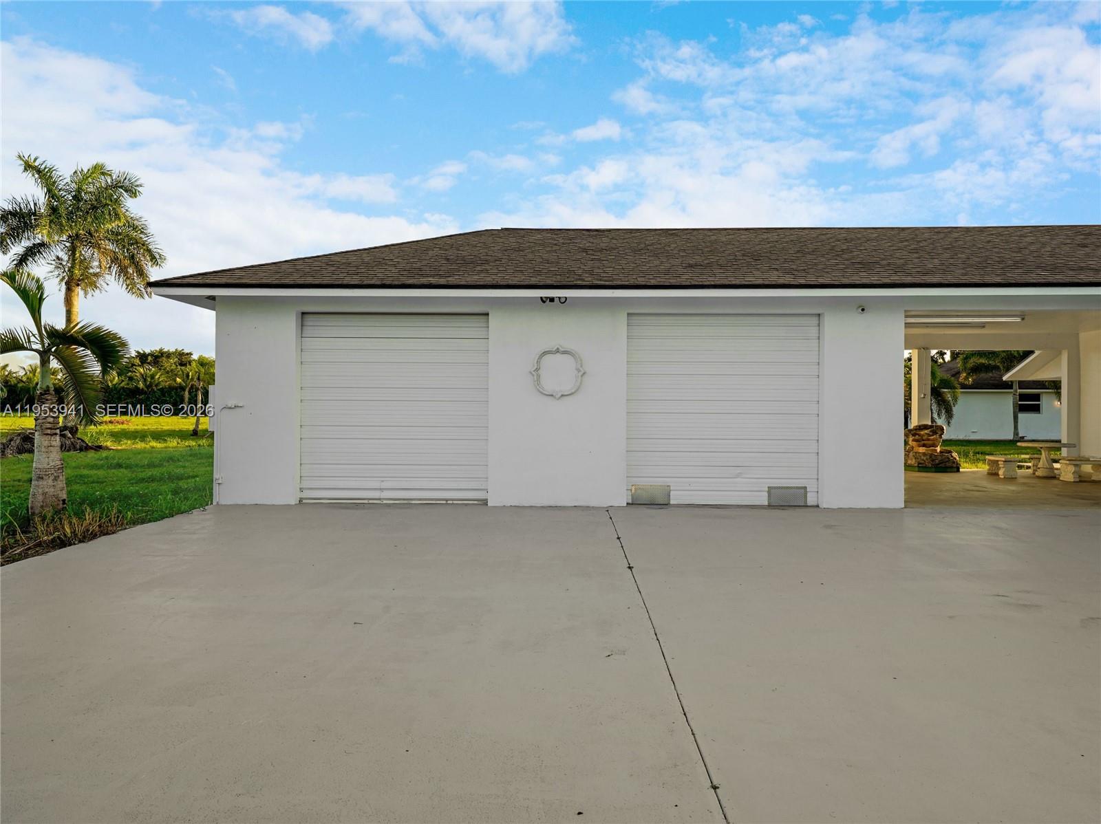 A white detached garage with two roll-up doors and an adjacent open-air patio area — 20000 SW 216th St, Miami FL 33170, MIAMI, FL
