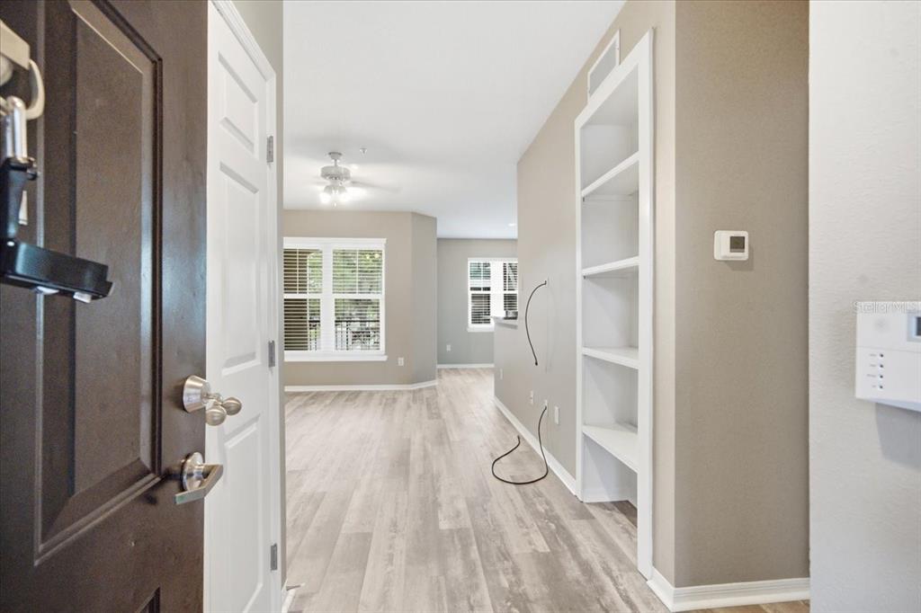 An entryway leads into a living area with light wood-look flooring and built-in shelving — 1910 E PALM AVENUE UNIT 10205, TAMPA, FL