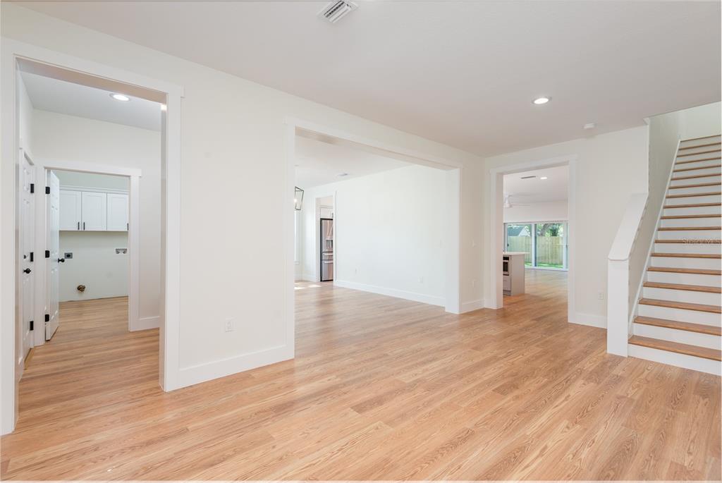 An interior view shows a bright living area with light wood floors and a staircase — 3414 W CHEROKEE AVENUE, TAMPA, FL