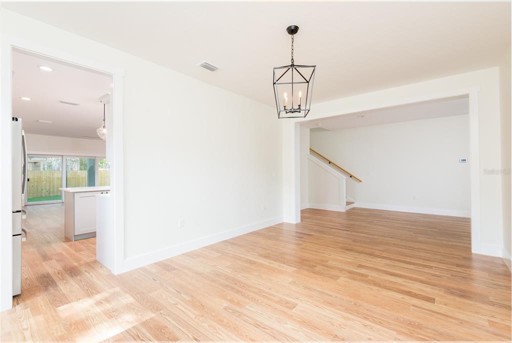 A dining area with light wood flooring, a black lantern chandelier, and an adjacent staircase — 3414 W CHEROKEE AVENUE, TAMPA, FL