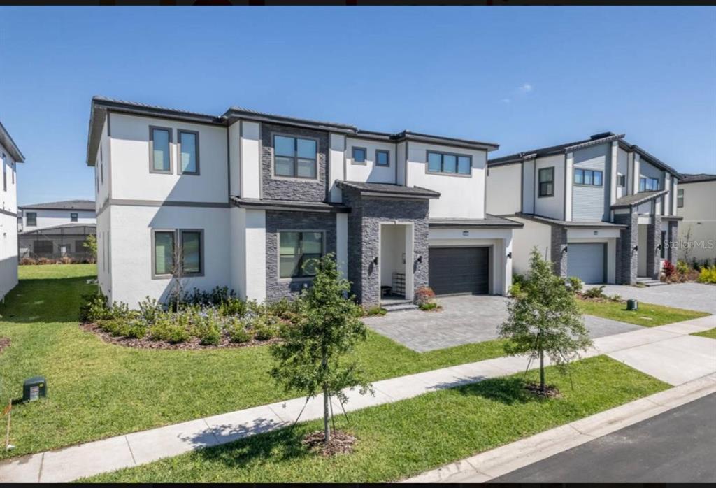 A two-story house with a white stucco exterior, stone accents, and a paved driveway — 6301 SAND SKIPPER ROAD, ORLANDO, FL